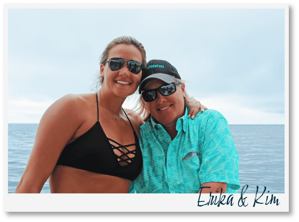 Erika and Kim close together smiling at the camera with the ocean in the background