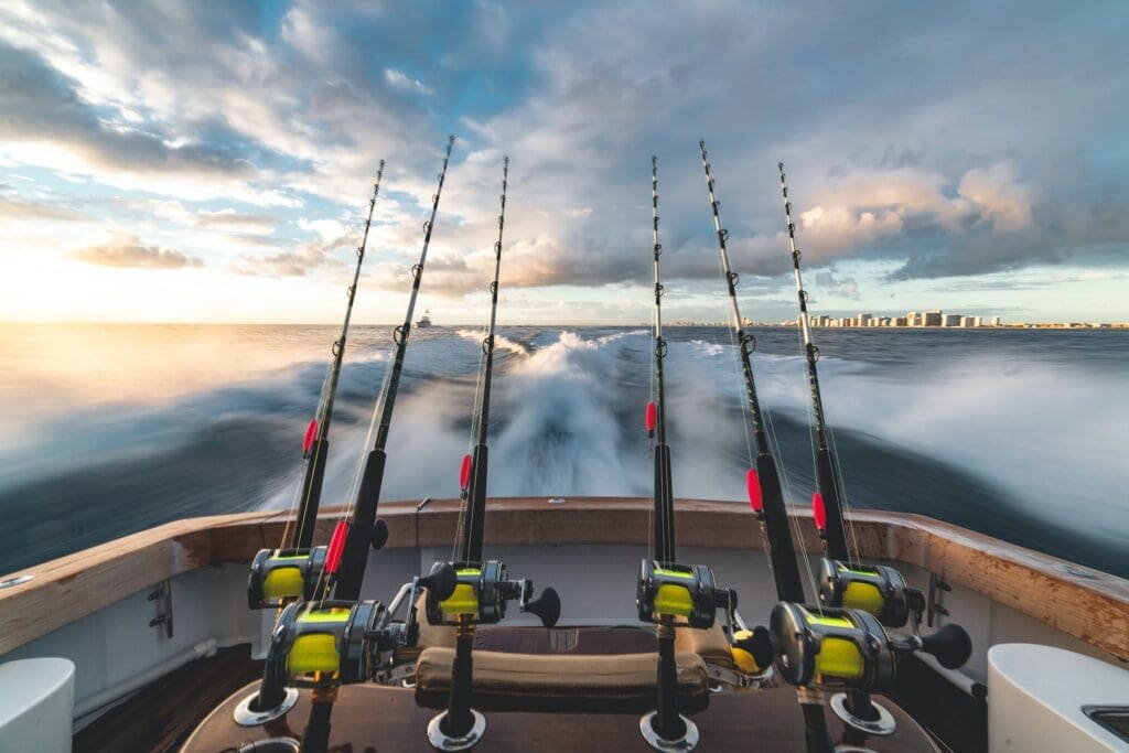 Fishing poles lined up on the back of a boat moving through the ocean