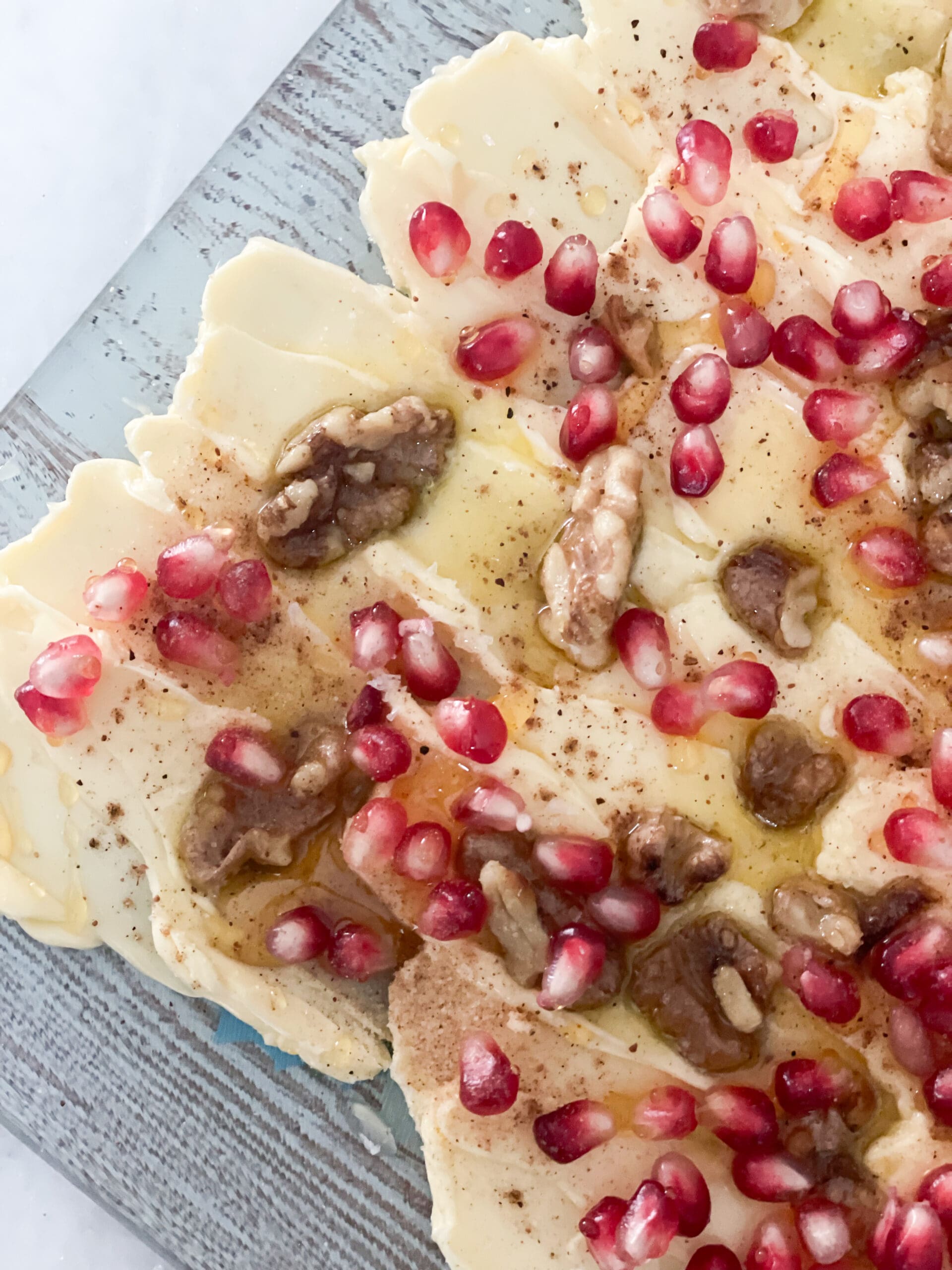 close up of butter board showing pomegranate seeds and walnuts