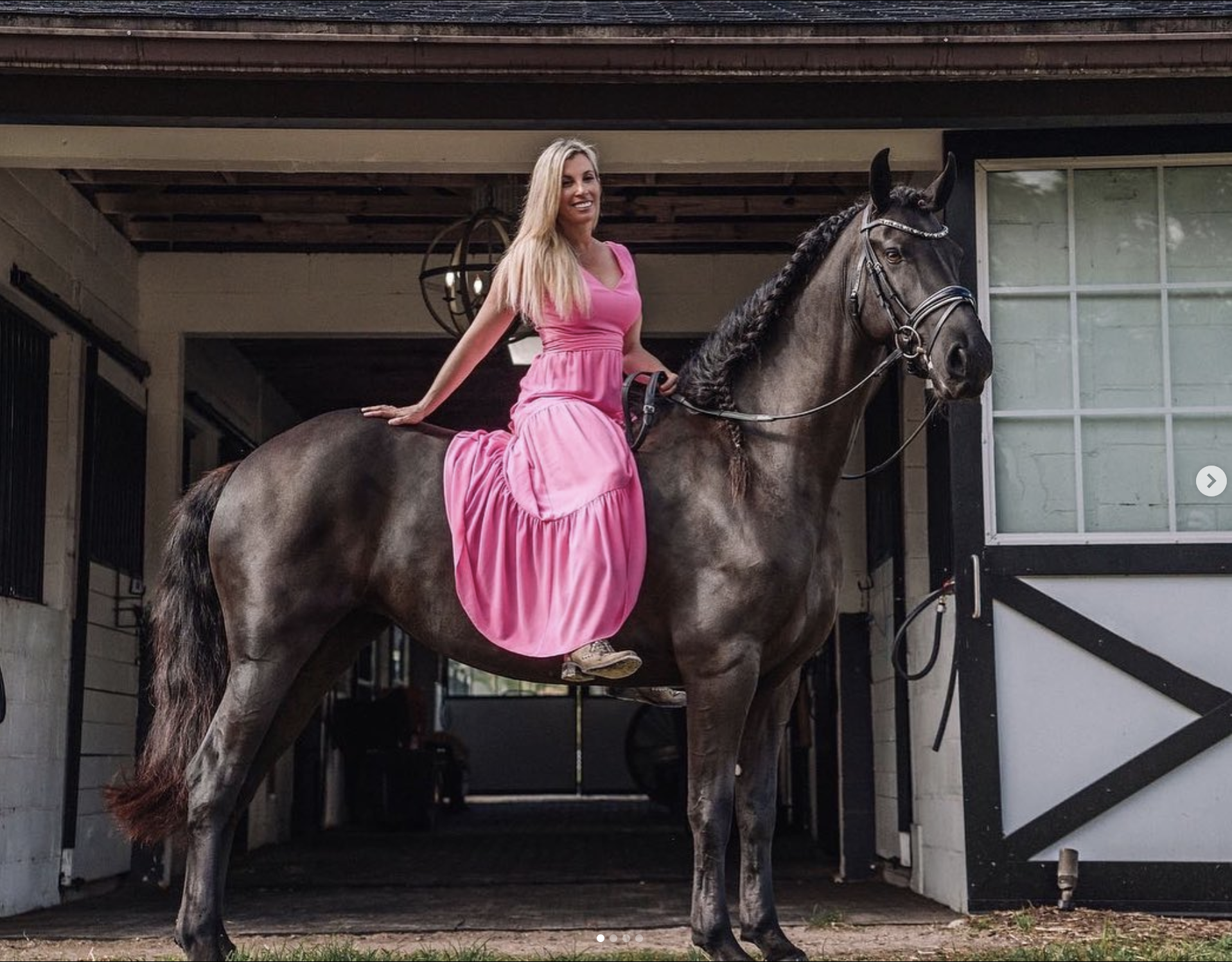 Monique Richter in pink dress sitting atop dark horse