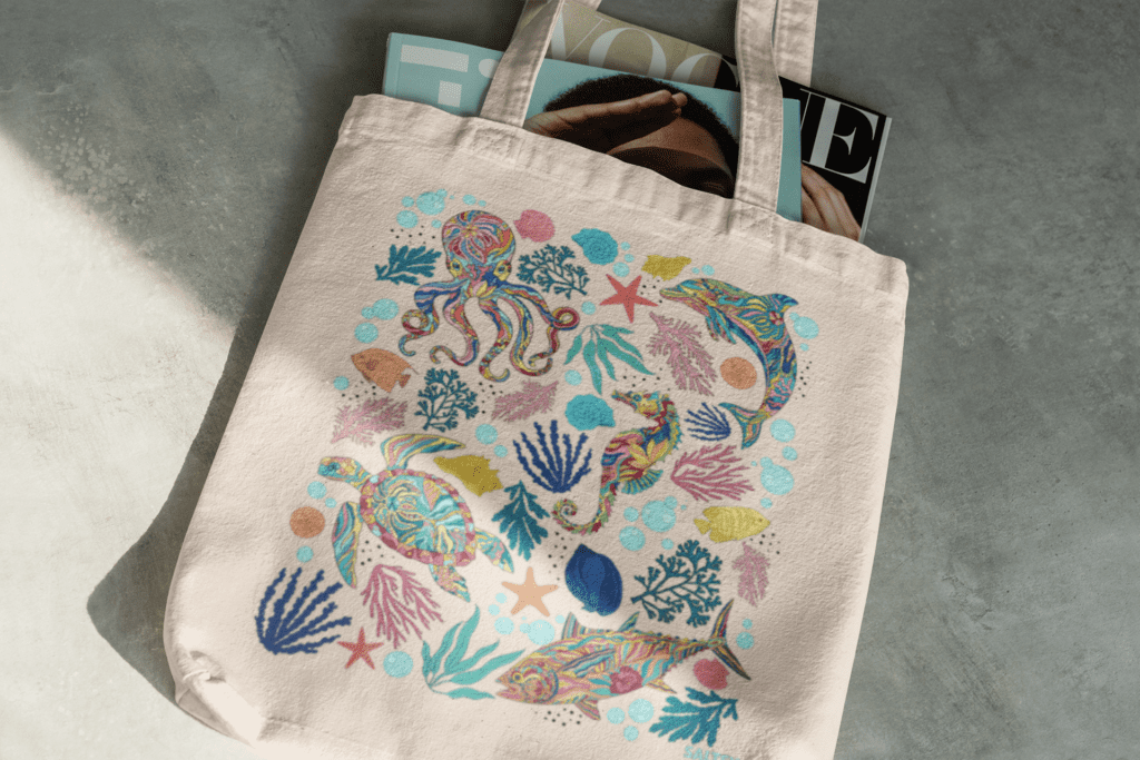 Sea menagerie canvas beach tote bag with colorful ocean artwork of a variety coral, shells, bubbles, creatures, and a blackfin tuna