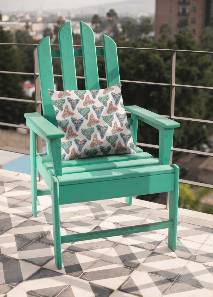 Tropical shark teeth patterned pillow by Saltsy sitting on turquoise adirondak chair. 