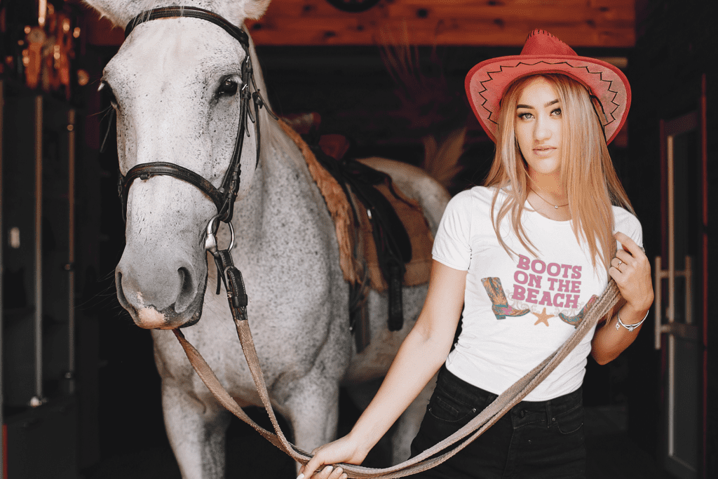 Woman wearing a Boots on the Beach tee holding a horse by its reigns